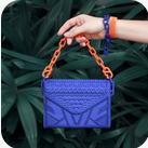 A person holding onto a blue purse with orange handles